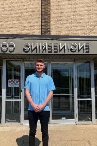Recent W&J alumnus Alex Donahue stands and smiles outside of Bloom Engineering Company.